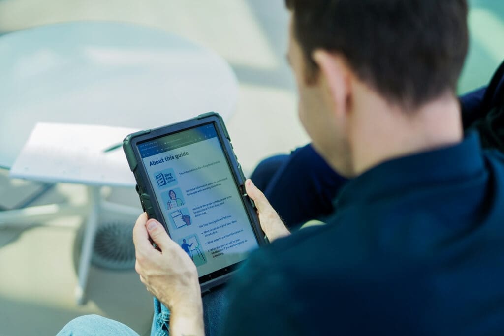 View all results Person with less-visible disability reads EasyRead guide on tablet device