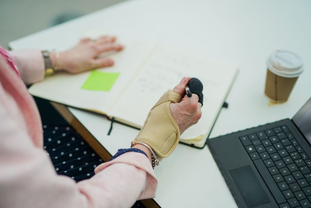 A person writing in a notebook wearing a wrist support