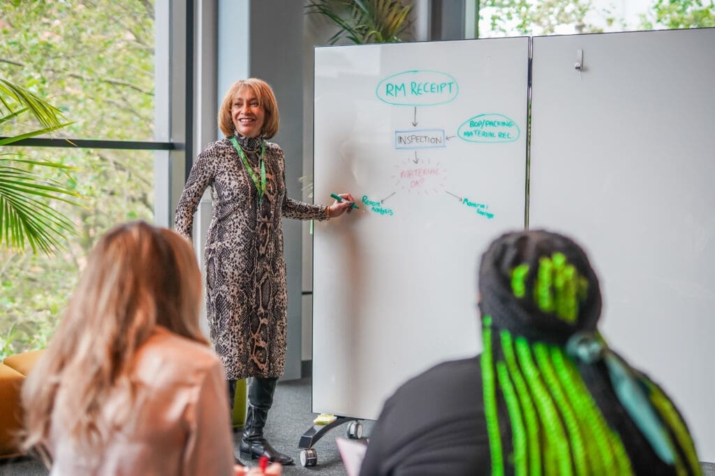 Person with less-visible disability runs meeting standing next to whiteboard