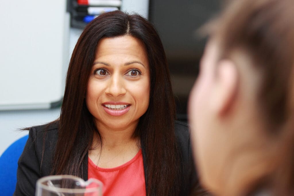Woman smiling while speaking to another person .