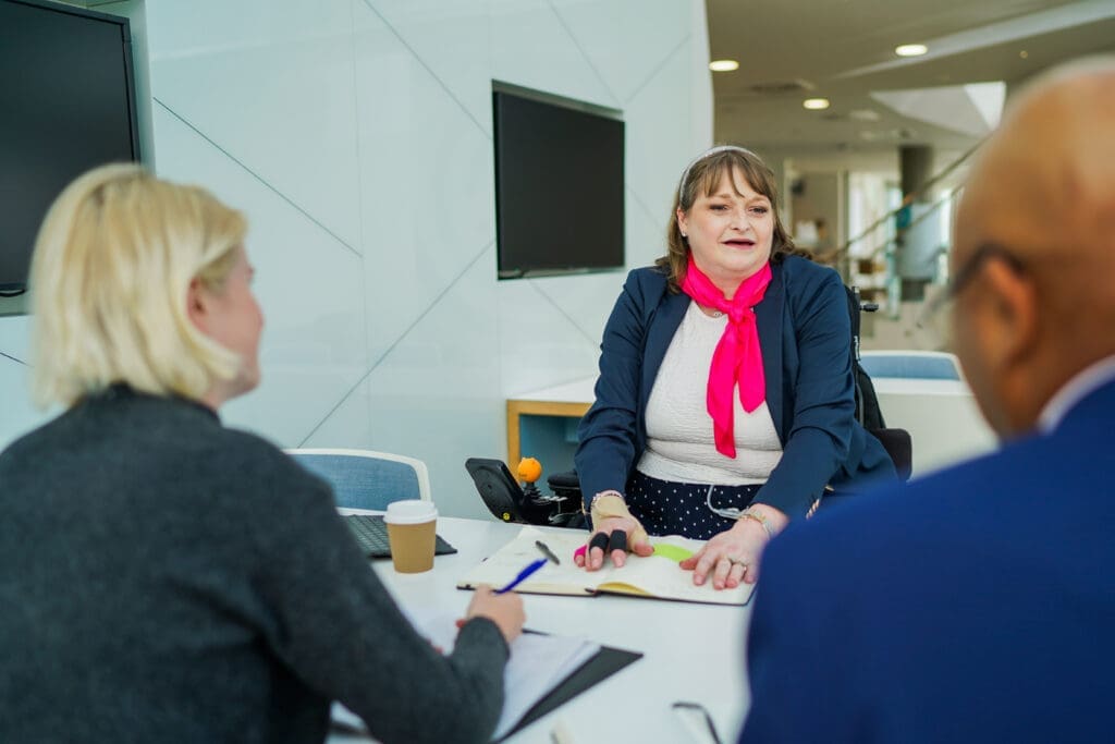 A wheelchair user in a meeting with two other people.