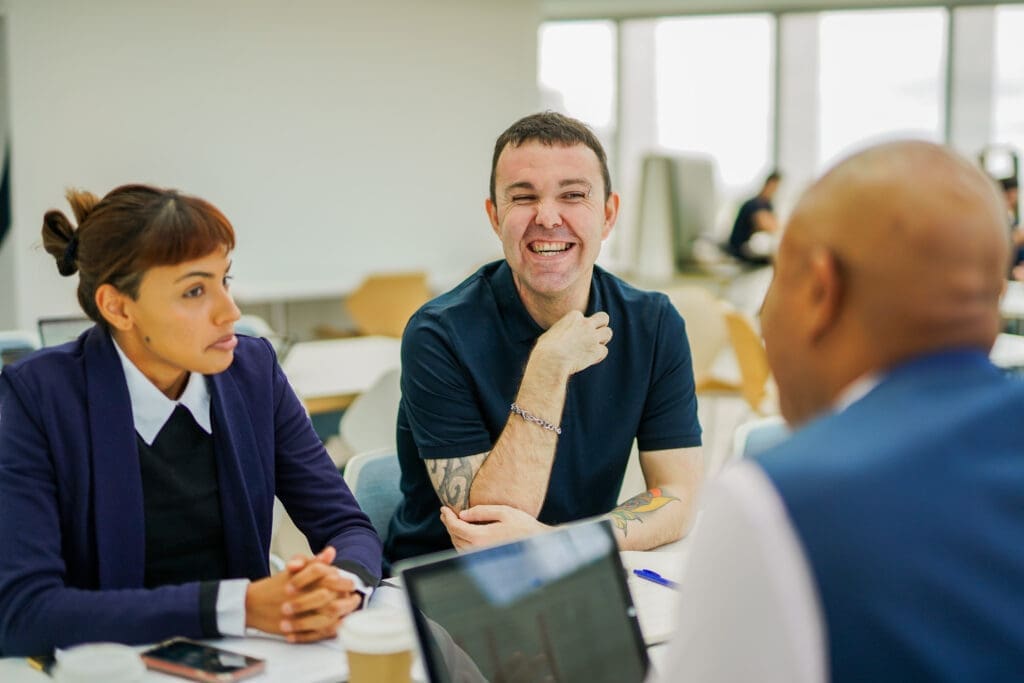 Three colleagues with less-visible disabilities chat together in office