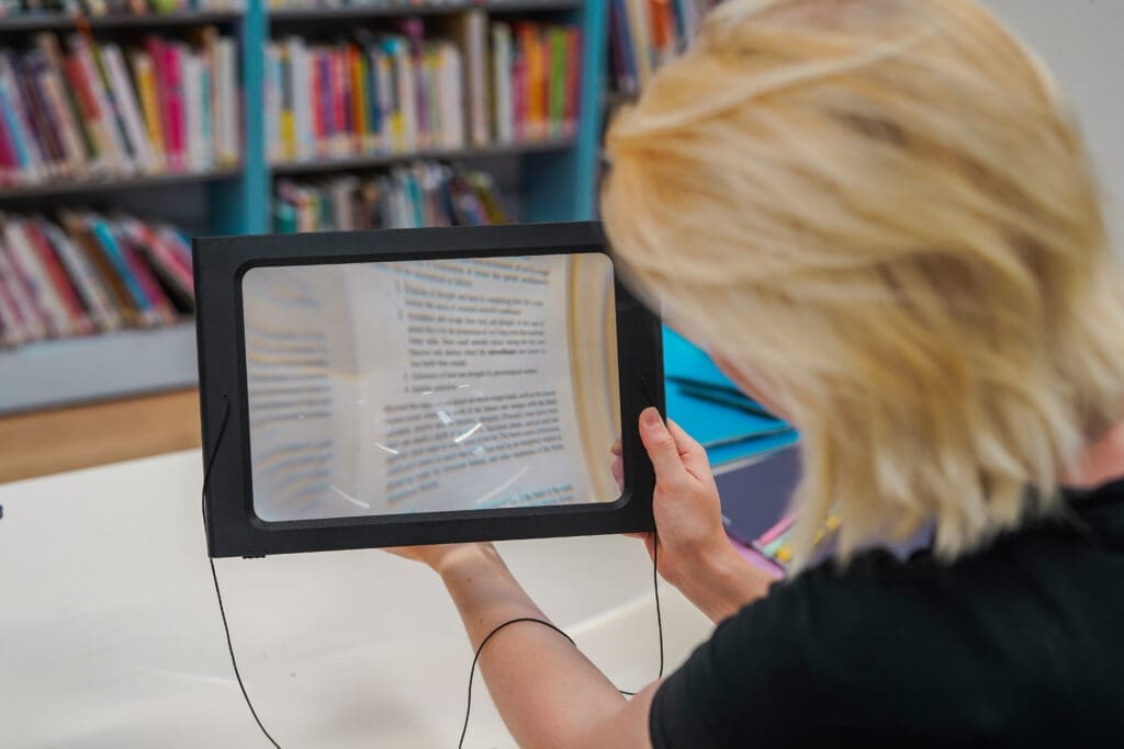 Person with sight loss holds an assistive reader magnifying glas