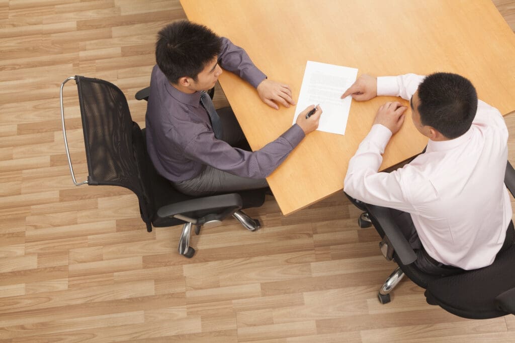 Two colleagues signing a contract in a meeting room.