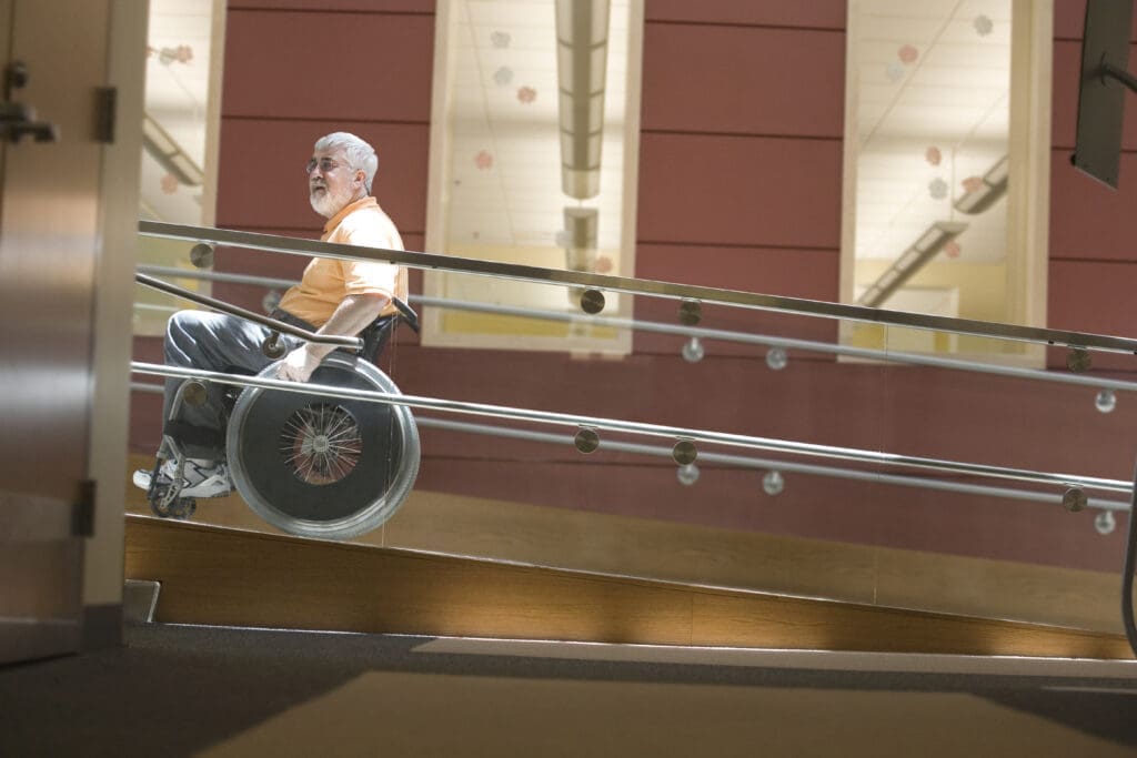 Older wheelchair user uses a ramp.