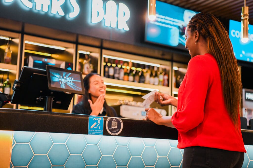 Deaf sales assistant uses sign language to thank customer at cinema.