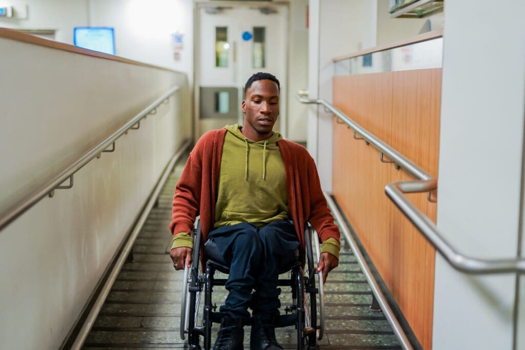Wheelchair user wheels down an interior ramp.