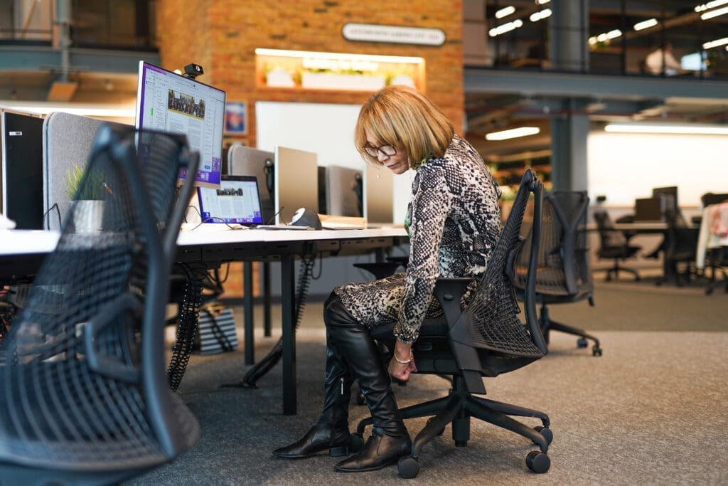 Person with less-visible disability adjusts desk chair in office