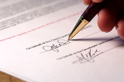 A hand signs a document.