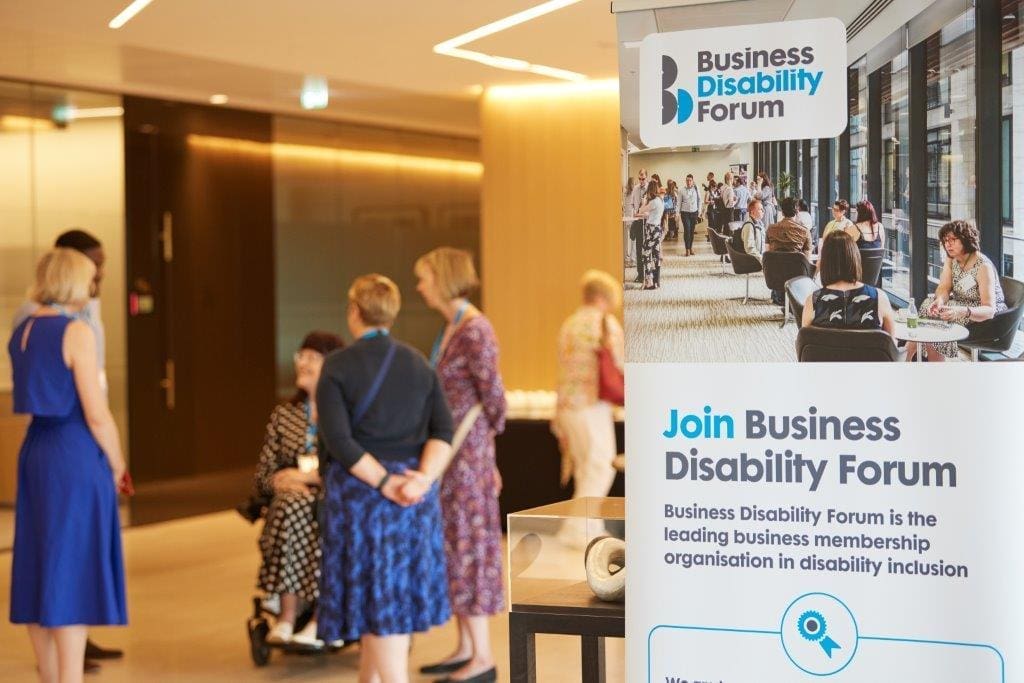 Delegates networking at an event next to BDF banner