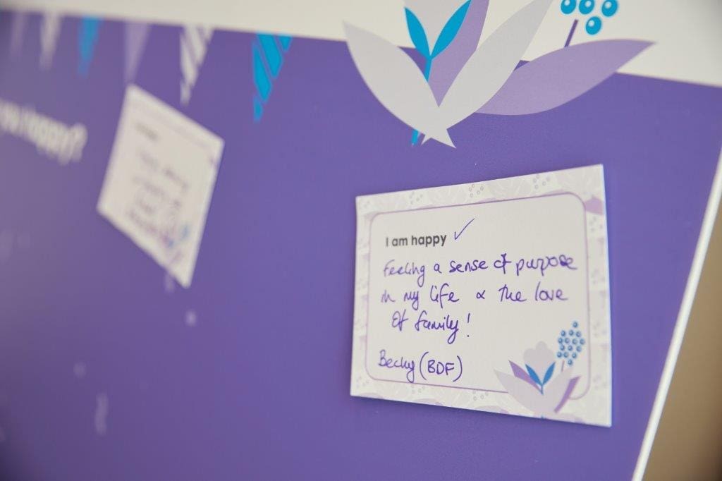 A handwritten note pinned to a board. It reads: 'I am happy feeling a sense of purpose in my life and true love from family! - Becky (BDF)'