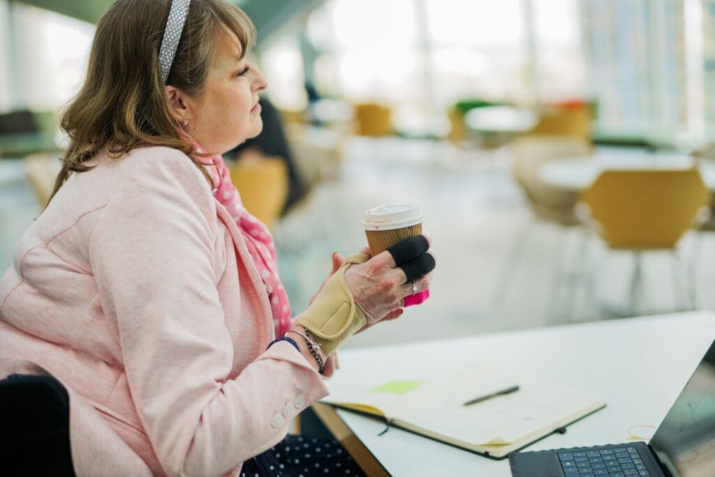 A wheelchair user drinking tea at a desk