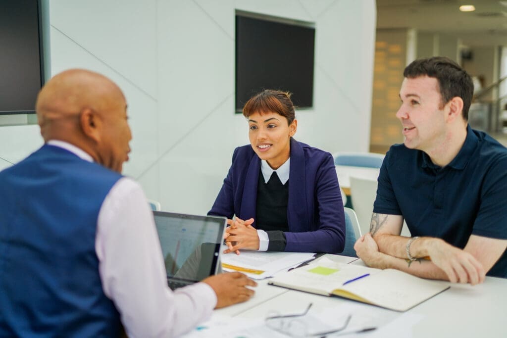 Person with less-visible disability smiles at meeting with colleagues in office.