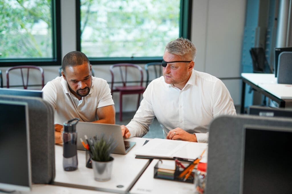 Man with facial difference works with colleague at desk
