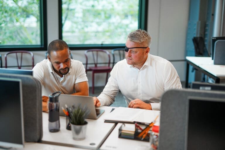 Man with facial difference works with colleague at desk