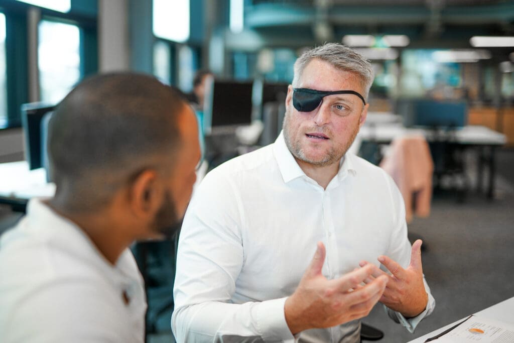 Man with facial difference interacts with colleague at desk