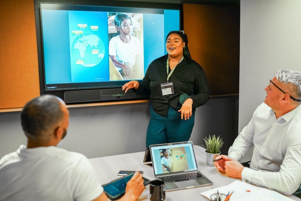 Person with less-visible disabilities delivers presentation to colleagues, one has sight loss
