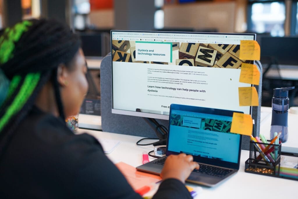 Person with dyslexia browses online resources using a computer with post-it notes on screen