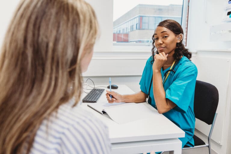 Deaf professional who wears hearing aid sits with patient in consultation