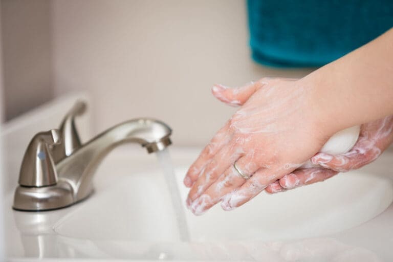 A close up of a person washing their hands in a sink with soap