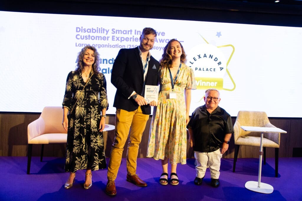The Alexandra Park and Palace team posing on stage with ceremony hosts Diane Lightfoot (left) and Simon Minty (right) after winning the Inclusive Customer Experience Award (large organisation) at the Disability Smart Awards 2025.