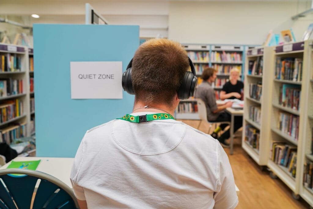 Man with autism studying at a quiet zone in a library wearing noise-cancelling headphones