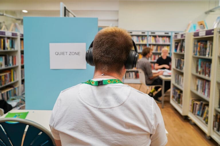 Man with autism studying at a quiet zone in a library wearing noise-cancelling headphones