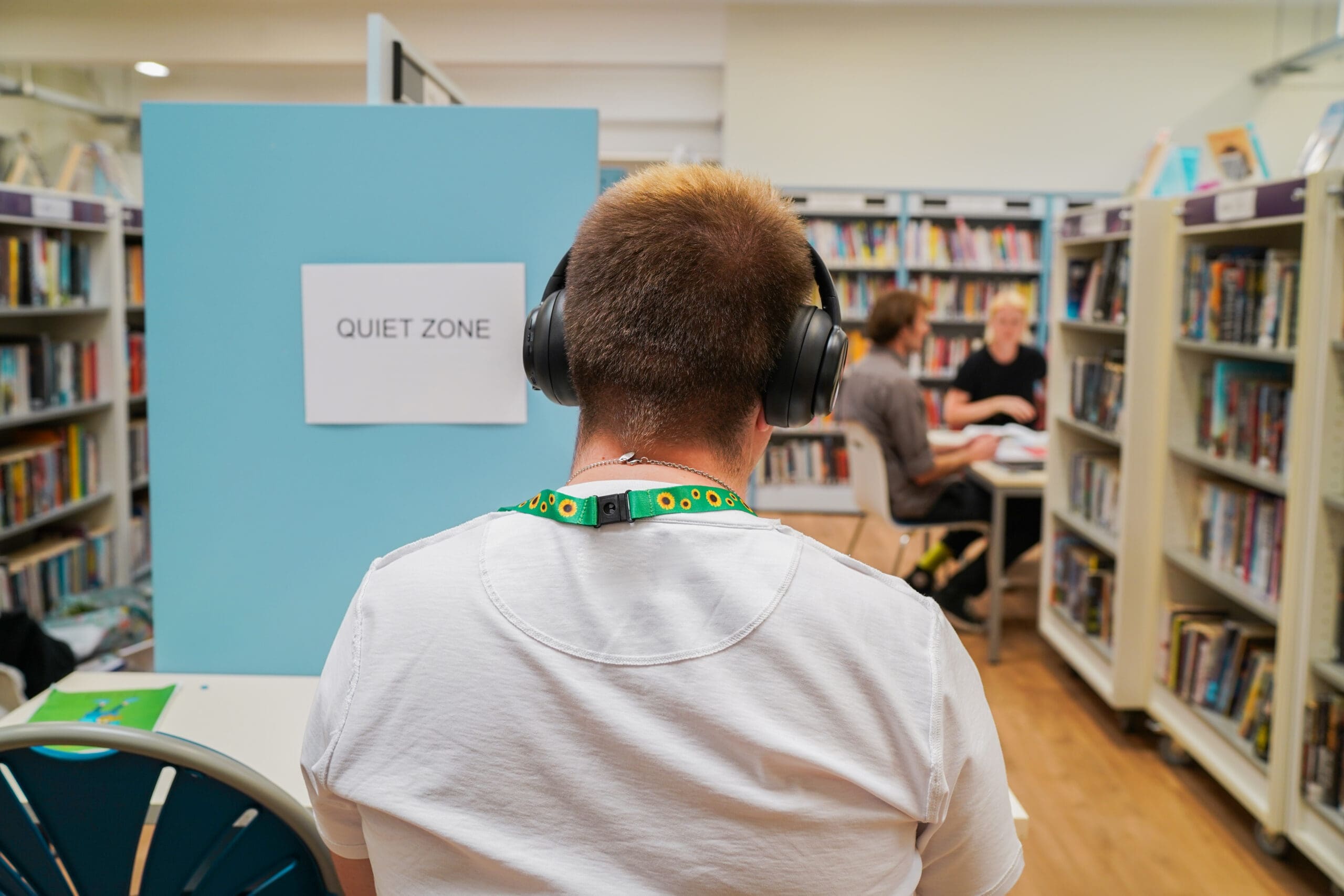 Man with autism studying at a quiet zone in a library wearing noise-cancelling headphones