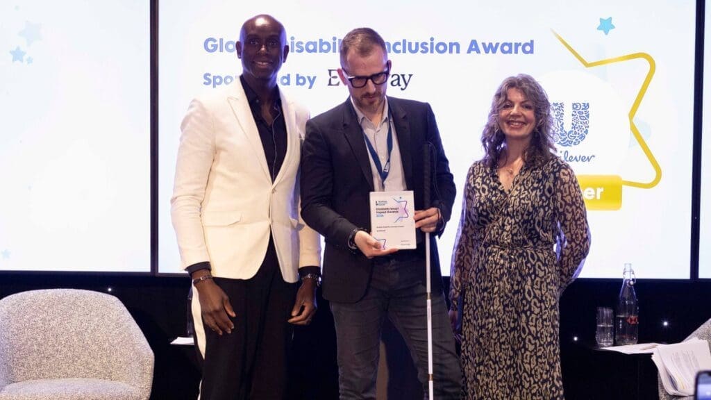 Unilever representative holding Global Disability Inclusion Award on stage with presenters at the Disability Smart Impact Awards 2026.