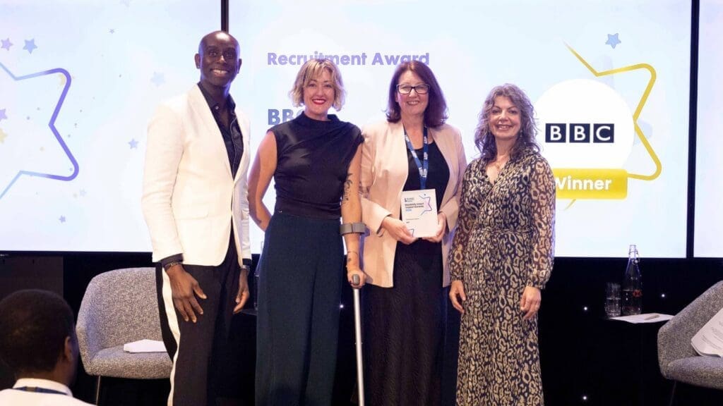 BBC team receiving Recruitment Award on stage with presenters at the Disability Smart Impact Awards 2026.