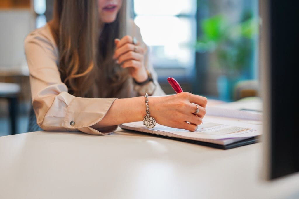 Person wearing medical information bracelet writes notes at desk at work