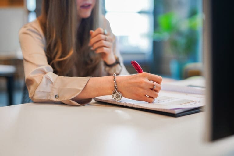 Person wearing medical information bracelet writes notes at desk at work